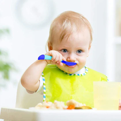 Toddler learning self-feeding with a smart spoon, promoting independence and confidence.